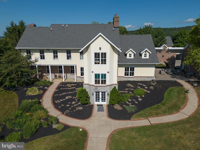 rear view of property featuring a chimney, french doors, and stone siding