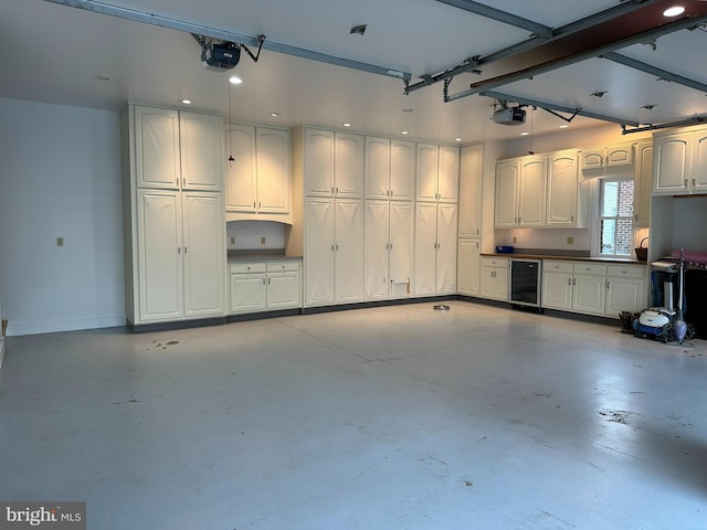 garage with a garage door opener, wine cooler, and baseboards