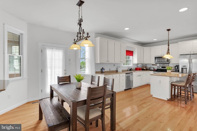 kitchen featuring visible vents, stainless steel appliances, a kitchen island, white cabinetry, and light wood-type flooring