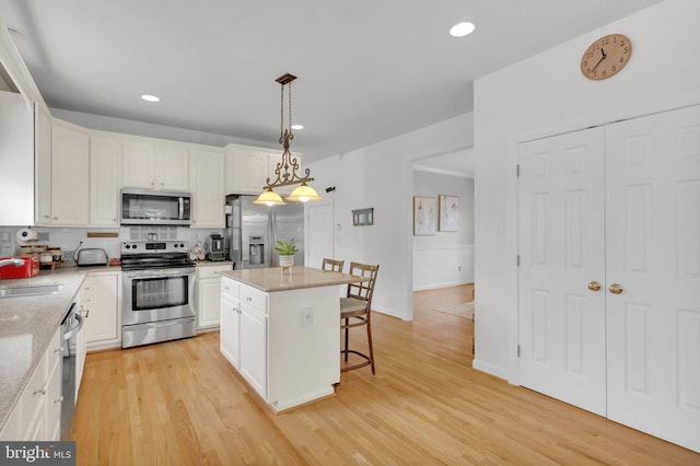 kitchen with stainless steel appliances, white cabinets, backsplash, a kitchen bar, and a sink