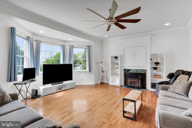 living area with recessed lighting, a premium fireplace, light wood-style floors, ceiling fan, and ornamental molding
