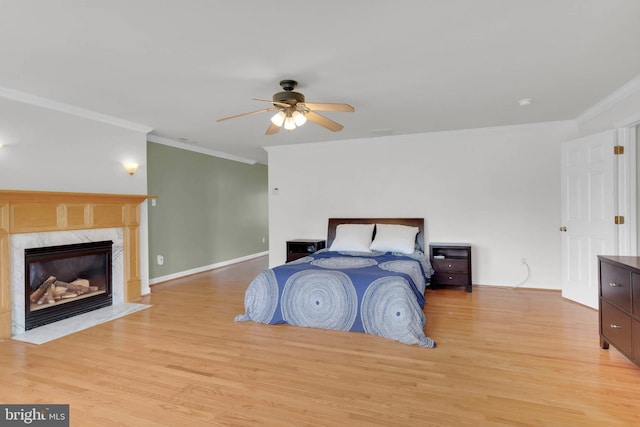 bedroom with a ceiling fan, ornamental molding, a high end fireplace, and light wood finished floors