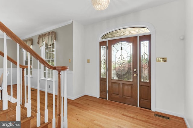 foyer entrance with a notable chandelier, light wood-style flooring, visible vents, and a wealth of natural light