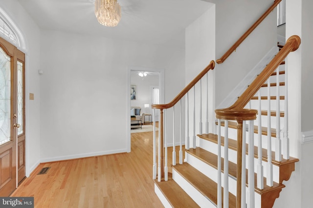 foyer entrance with wood finished floors, an inviting chandelier, and stairs