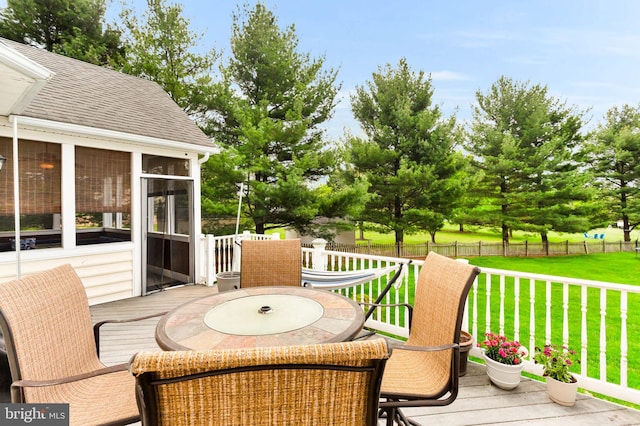 deck with fence, outdoor dining space, a sunroom, and a lawn