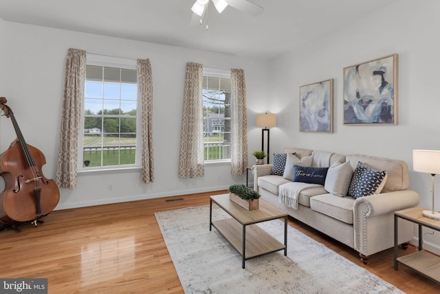 living area featuring wood finished floors, a ceiling fan, visible vents, and baseboards