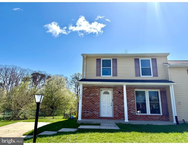 view of front of property with brick siding, a front lawn, and fence