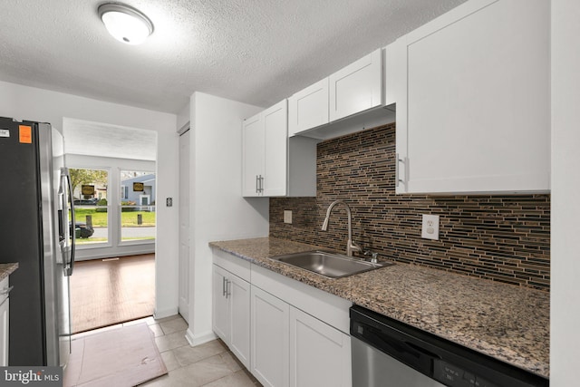 kitchen with tasteful backsplash, a sink, light tile patterned floors, white cabinets, and appliances with stainless steel finishes