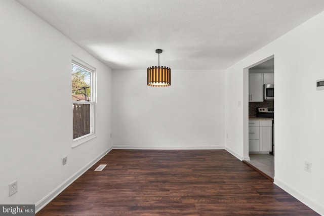 unfurnished dining area featuring baseboards, visible vents, and dark wood-style flooring