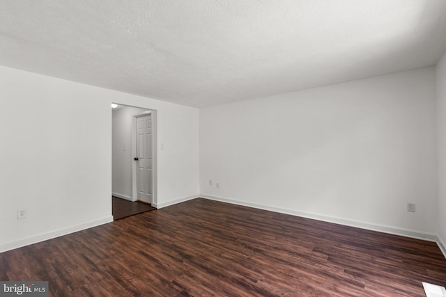 spare room featuring baseboards, dark wood-type flooring, and a textured ceiling