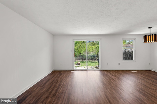 empty room with baseboards, a textured ceiling, and dark wood-type flooring