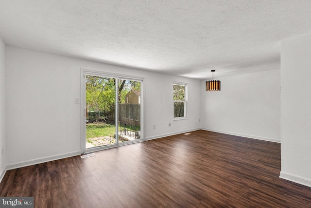 spare room with visible vents, baseboards, dark wood-style floors, and a textured ceiling