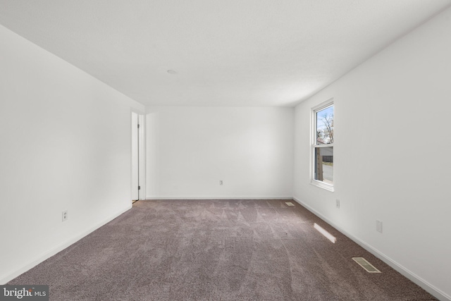 empty room featuring carpet, visible vents, and baseboards
