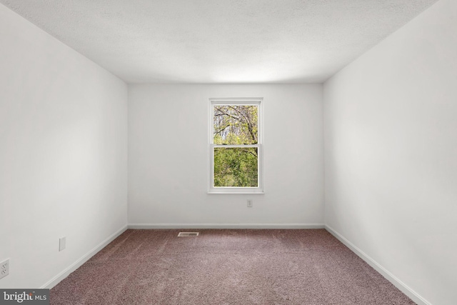 carpeted empty room with baseboards, a textured ceiling, and visible vents