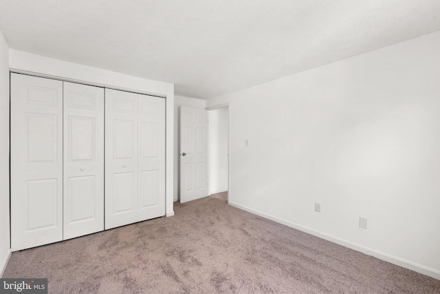 unfurnished bedroom with a closet, carpet flooring, and baseboards