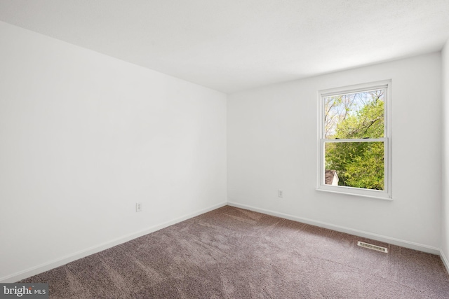 carpeted spare room with baseboards and visible vents