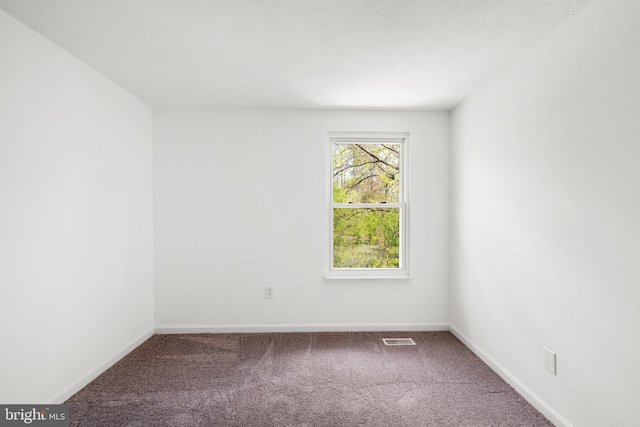 carpeted spare room with visible vents and baseboards