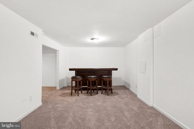 dining space with baseboards, carpet floors, visible vents, and a dry bar