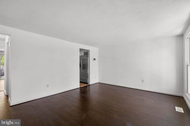 empty room with visible vents, baseboards, wood finished floors, and a textured ceiling