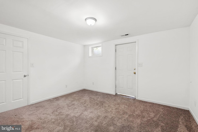 spare room featuring carpet floors, visible vents, and baseboards