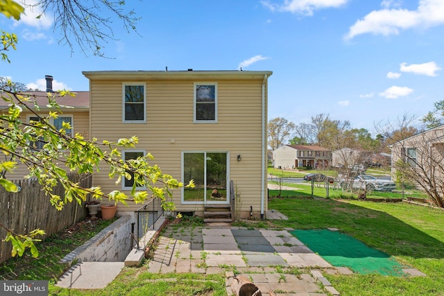 back of property with fence, entry steps, and a yard
