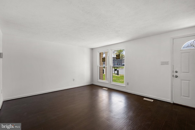 entrance foyer featuring baseboards, a textured ceiling, and dark wood finished floors
