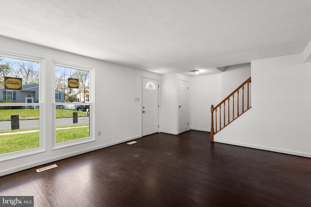 foyer entrance with dark wood-style floors, baseboards, visible vents, and stairs