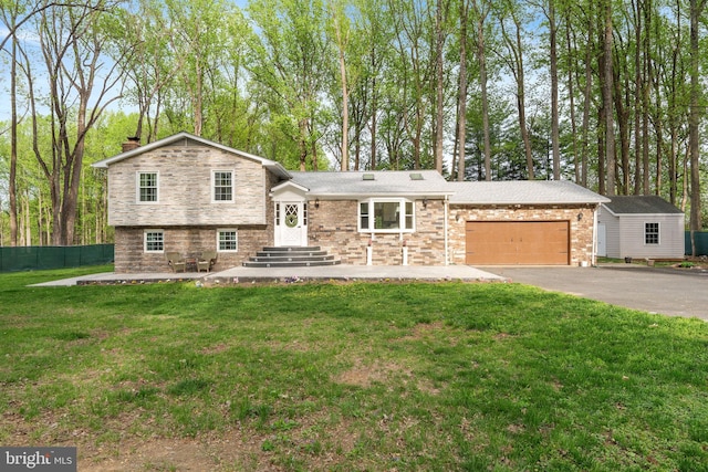 split level home with a chimney, fence, an attached garage, driveway, and a front yard