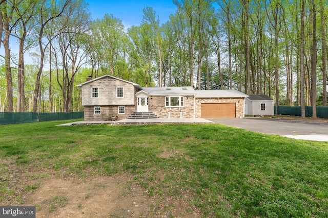 tri-level home featuring a chimney, driveway, stone siding, fence, and a garage