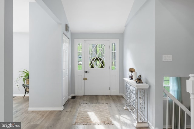entrance foyer with plenty of natural light, vaulted ceiling, wood finished floors, and baseboards