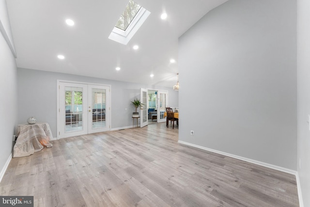 unfurnished living room with lofted ceiling with skylight, a healthy amount of sunlight, baseboards, and french doors