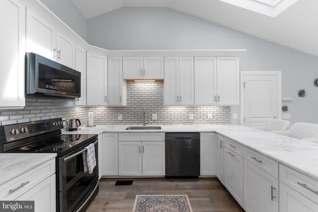 kitchen with lofted ceiling with skylight, a sink, dishwasher, double oven range, and white cabinets