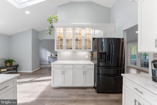 kitchen featuring white cabinets, lofted ceiling with skylight, and fridge with ice dispenser