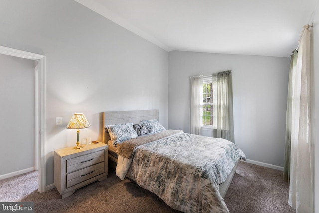 bedroom with dark carpet, lofted ceiling, and baseboards