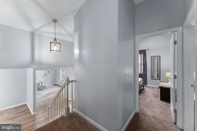 hall with a towering ceiling, baseboards, an upstairs landing, and carpet flooring