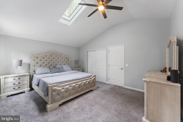 carpeted bedroom featuring vaulted ceiling with skylight, a ceiling fan, and baseboards