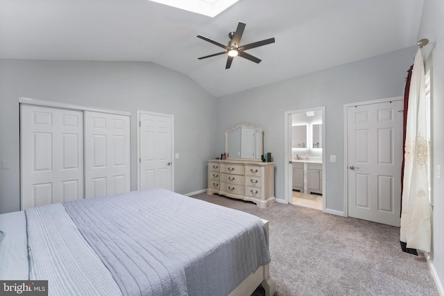 bedroom featuring lofted ceiling with skylight, a closet, baseboards, carpet flooring, and ceiling fan