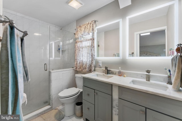 full bathroom with toilet, a sink, double vanity, and a stall shower