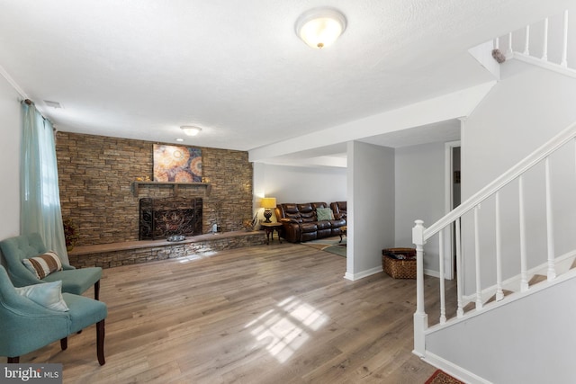 living room featuring a fireplace, wood finished floors, visible vents, and stairs