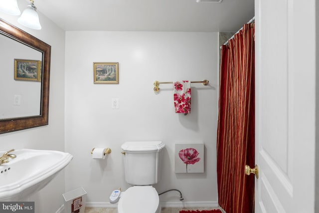 bathroom with baseboards, a sink, and toilet