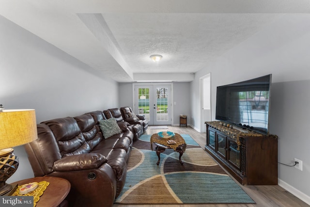 living room with light wood-style floors, a textured ceiling, baseboards, and french doors