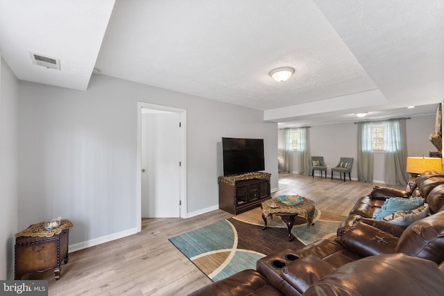 living area with baseboards, wood finished floors, visible vents, and a textured ceiling