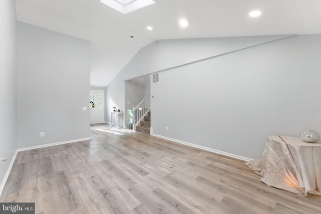 unfurnished living room featuring stairway, lofted ceiling with skylight, baseboards, visible vents, and recessed lighting