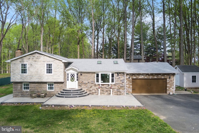 tri-level home featuring an attached garage, a chimney, aphalt driveway, and stone siding