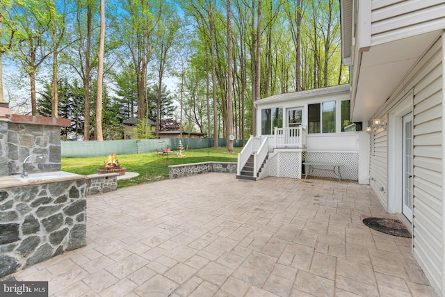 view of patio / terrace with stairs, a fenced backyard, an outdoor fire pit, a sunroom, and a deck