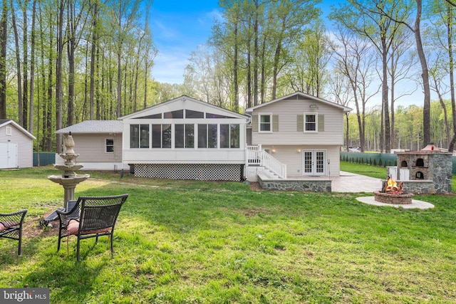back of house with french doors, a fire pit, a yard, a patio, and a sunroom