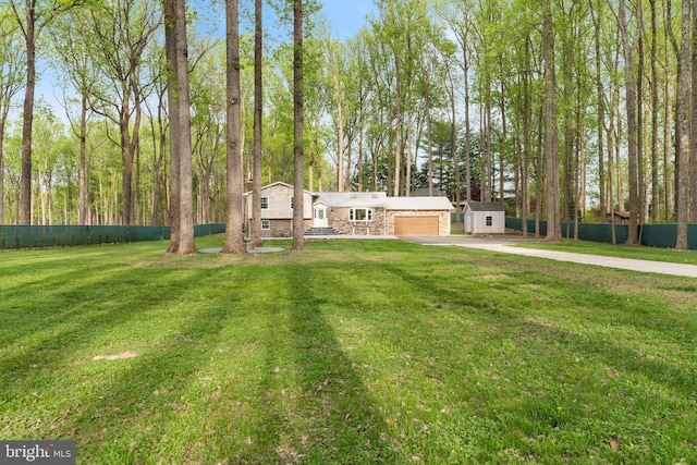 view of front of home with an attached garage, a front yard, concrete driveway, and fence