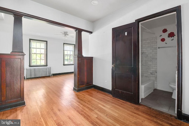 2728 Minnesota Ave SE, Washington, DC 20019 - interior space with light wood finished floors, radiator heating unit, a ceiling fan, baseboards, and decorative columns
