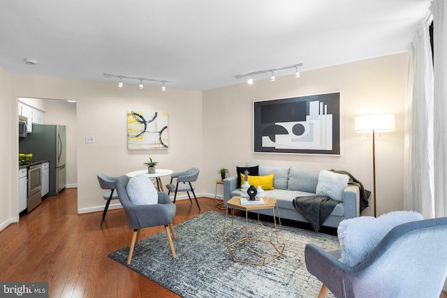 living area with wood finished floors, rail lighting, and baseboards