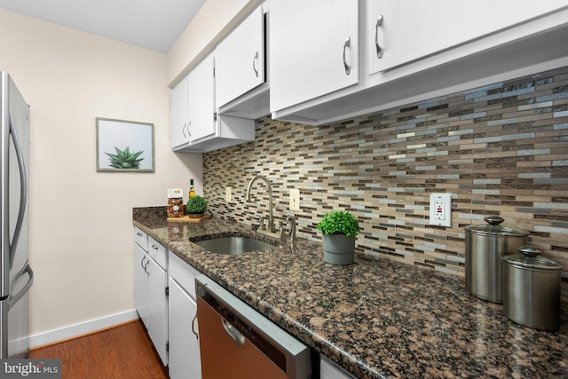 kitchen with baseboards, a sink, backsplash, and appliances with stainless steel finishes
